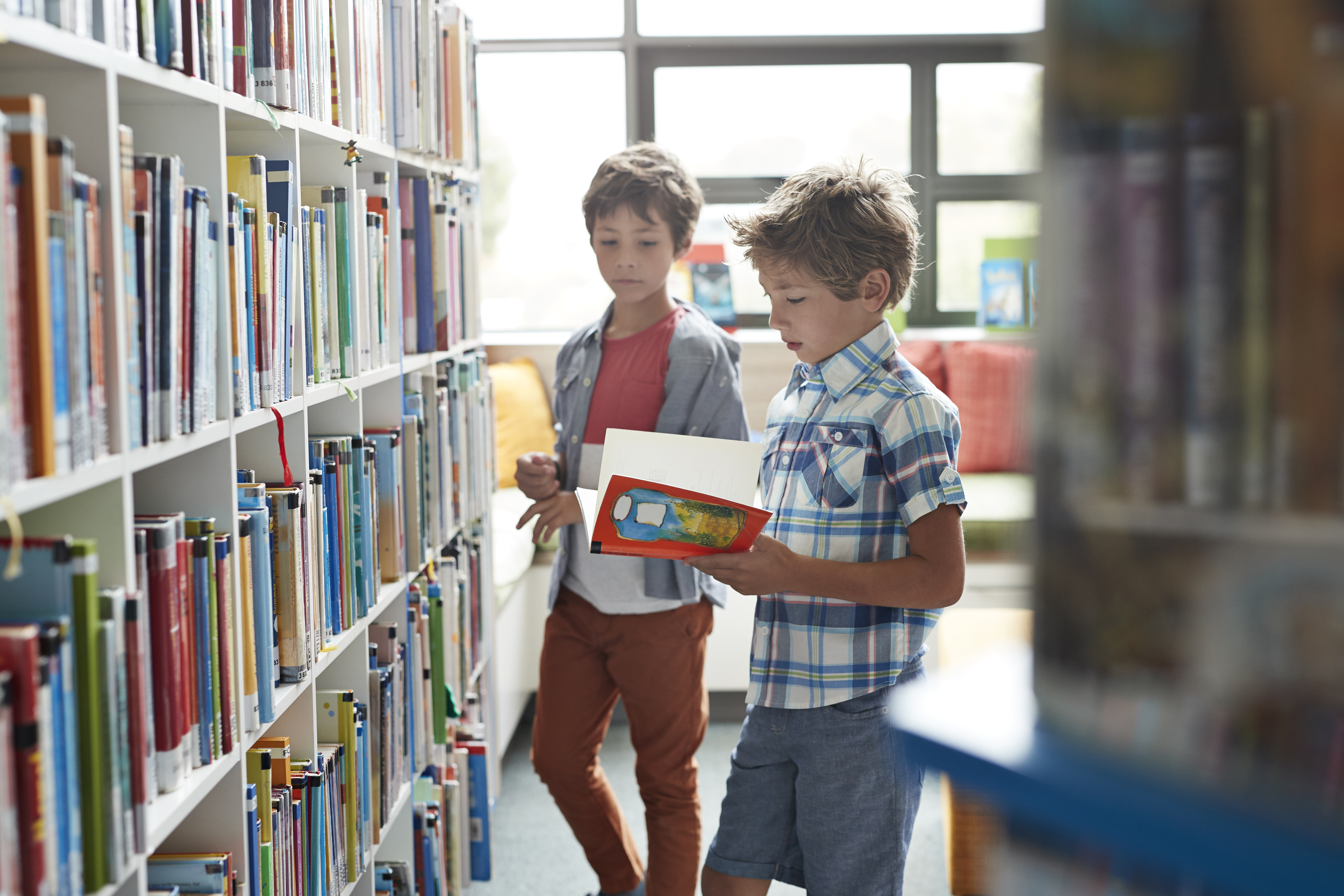 Two boys browsing books on library shelves