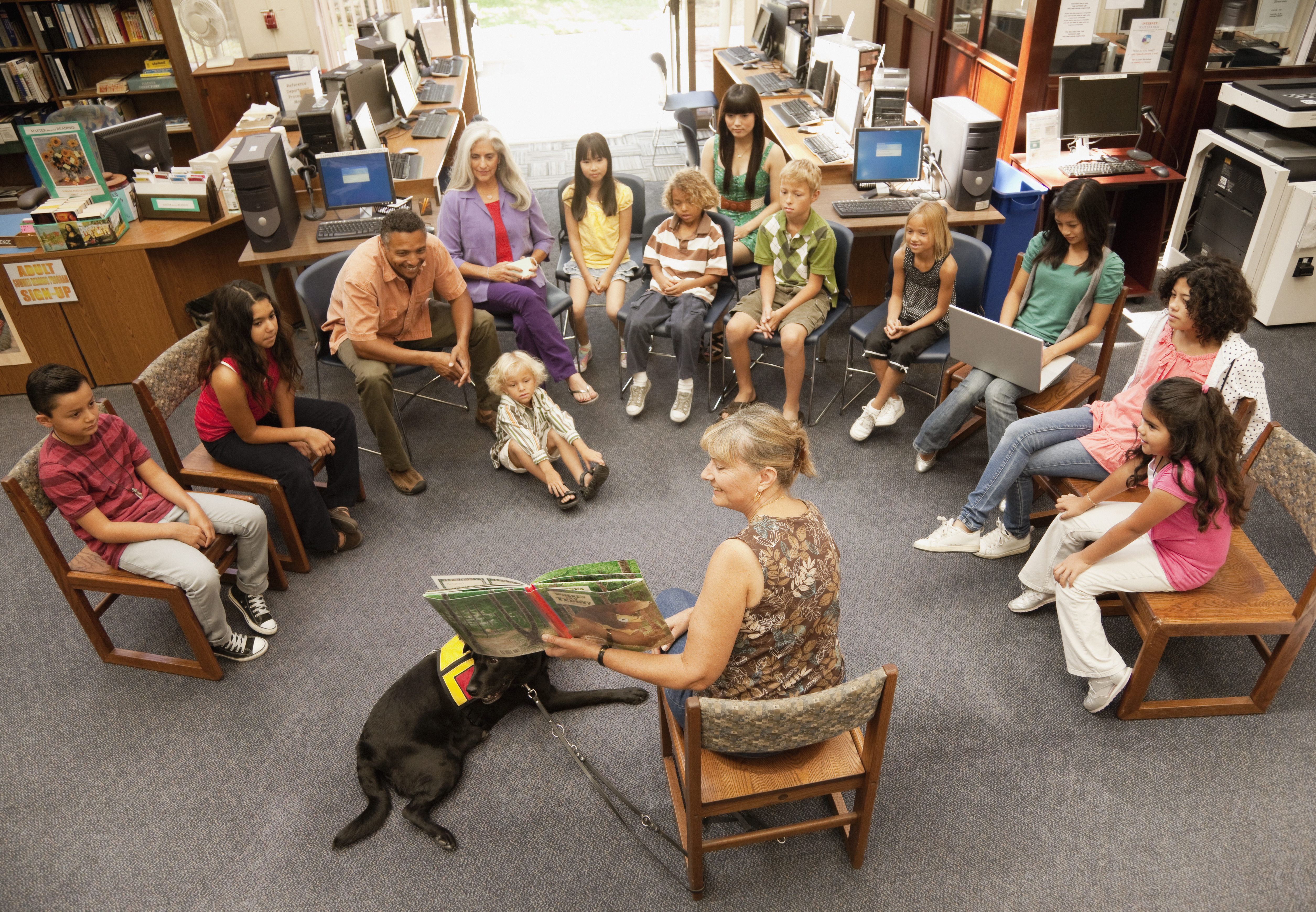 Librarian reading to a large circle of children and adults during storytime